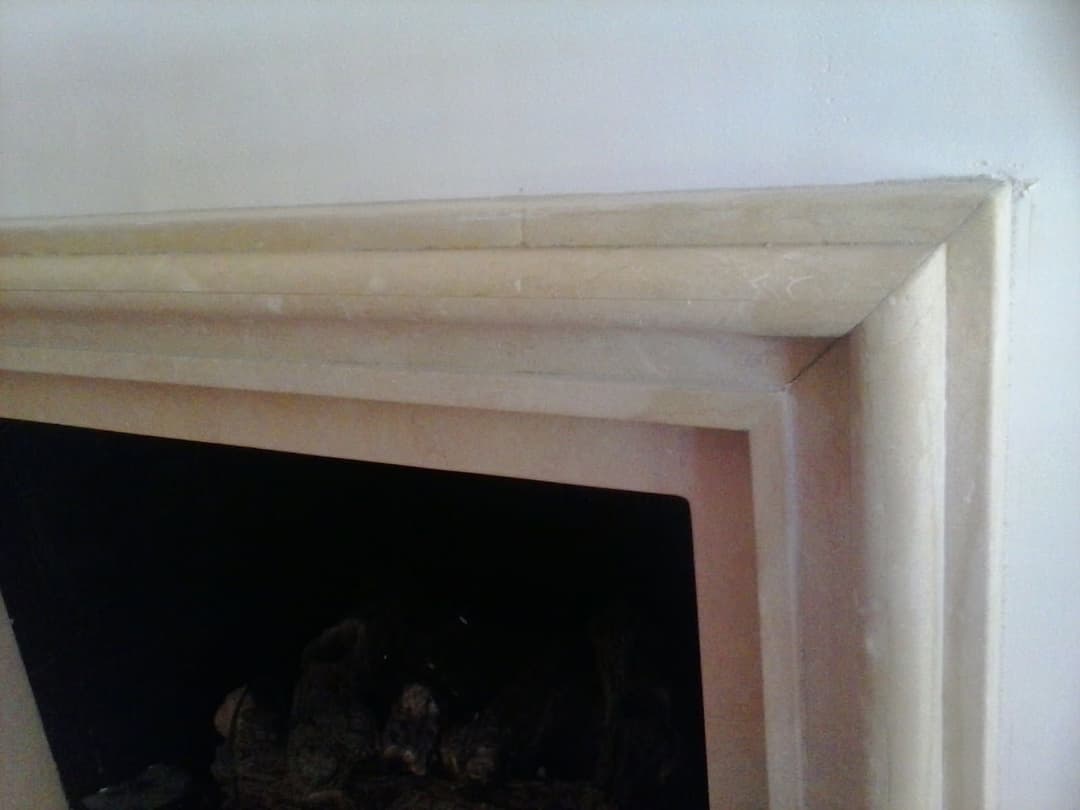 Elegant stone fireplace mantel with detailed edges and dark interior. Ideal for home decor.