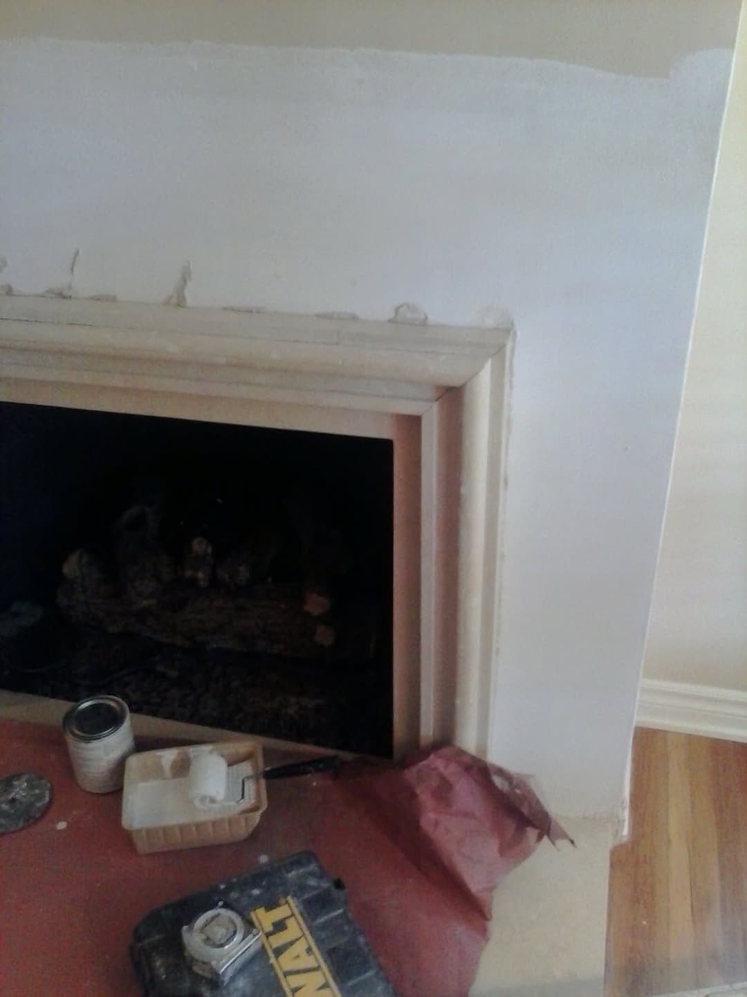 Fireplace renovation with tools and supplies, showcasing fresh paint and trim work.