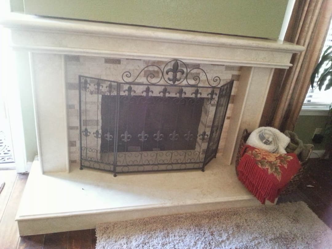 Elegant fireplace with decorative metal screen, neutral tones, and cozy decor elements.