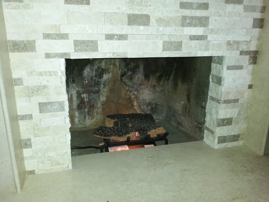 Indoor fireplace with modern stone surround and lit gas logs, creating a cozy ambiance.