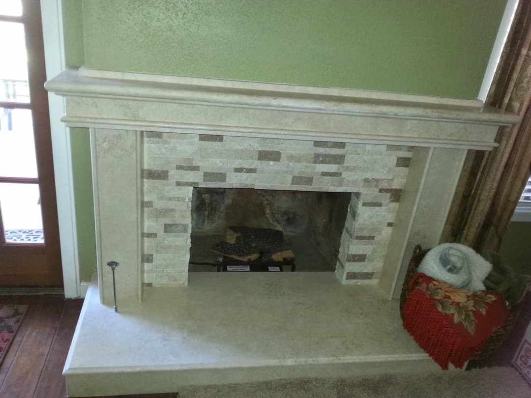 Elegant stone fireplace with mosaic tile accents in a cozy living room setting.