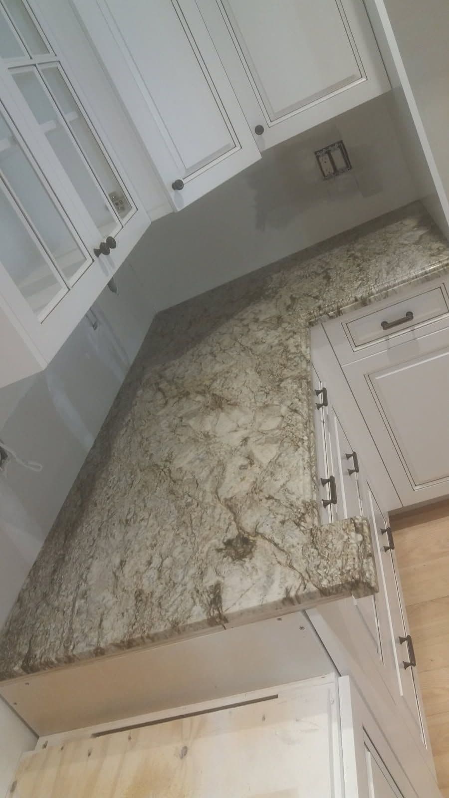 Granite countertop in modern kitchen with white cabinets and gray walls.
