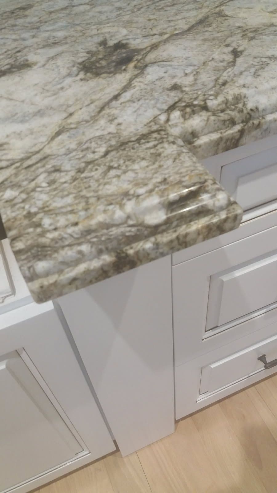 Granite countertop with natural patterns and a polished edge, paired with white cabinetry.