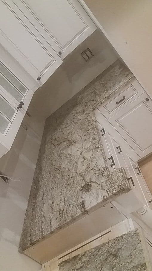 Granite kitchen countertop with light-colored cabinets and a modern design.