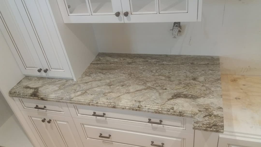 Granite countertop with intricate patterns in a kitchen setting, paired with white cabinetry.