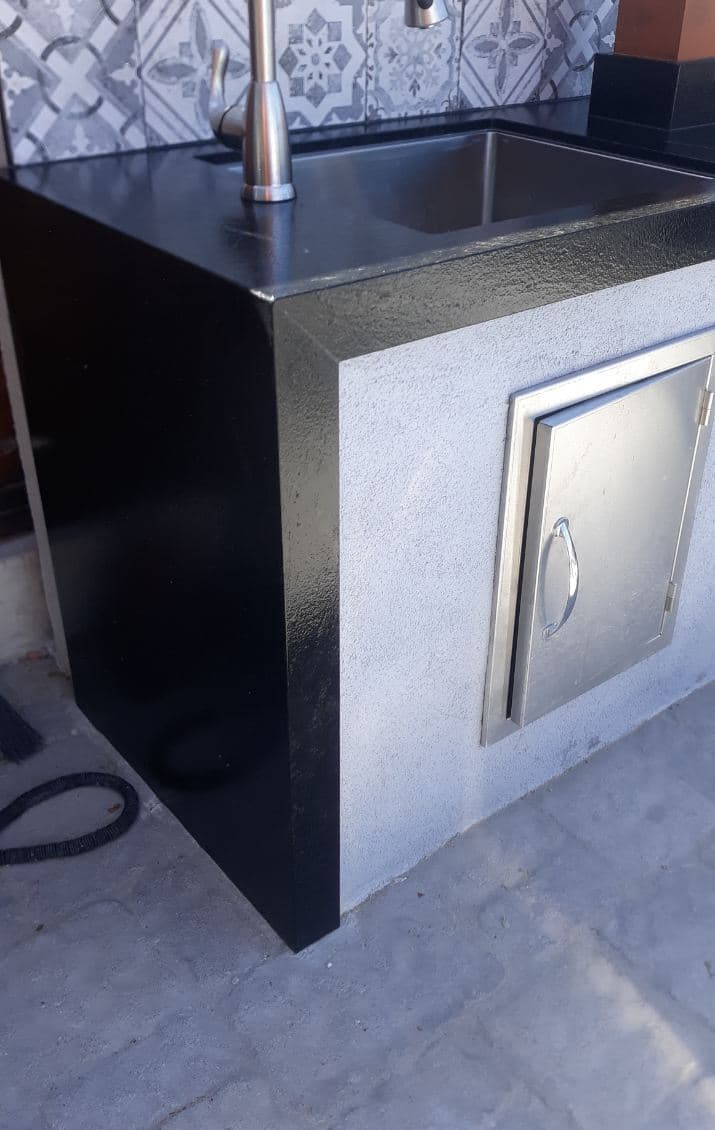 Modern outdoor sink with stainless steel faucet, black granite countertop, and storage cabinet.