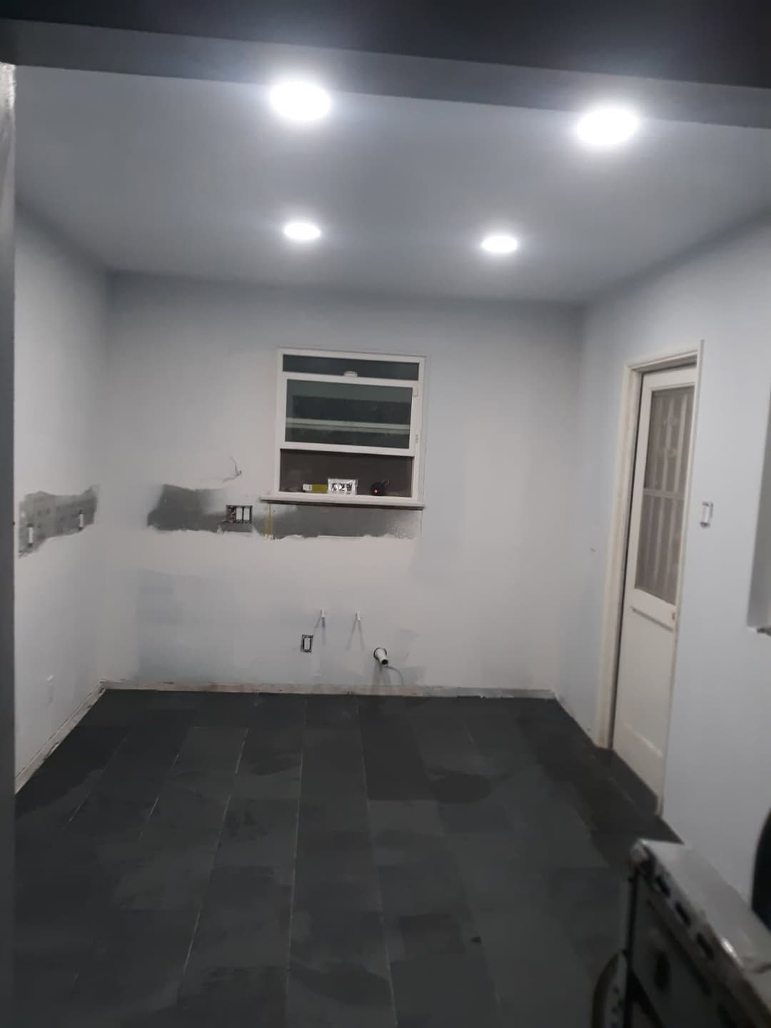Empty room with gray walls, recessed lighting, and a small window, ready for renovation.