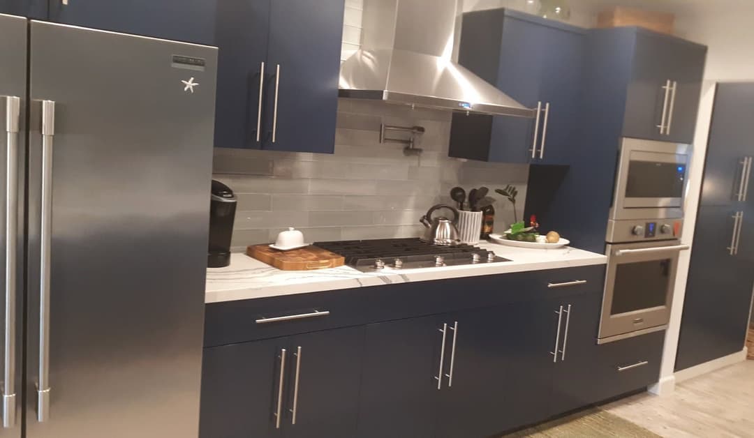 Modern kitchen with blue cabinets, stainless steel appliances, and a stylish countertop setup.