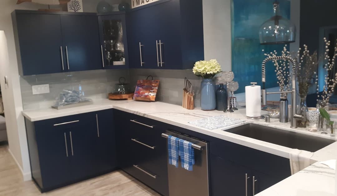 Modern kitchen with navy blue cabinets, white countertops, and stylish decor accents.