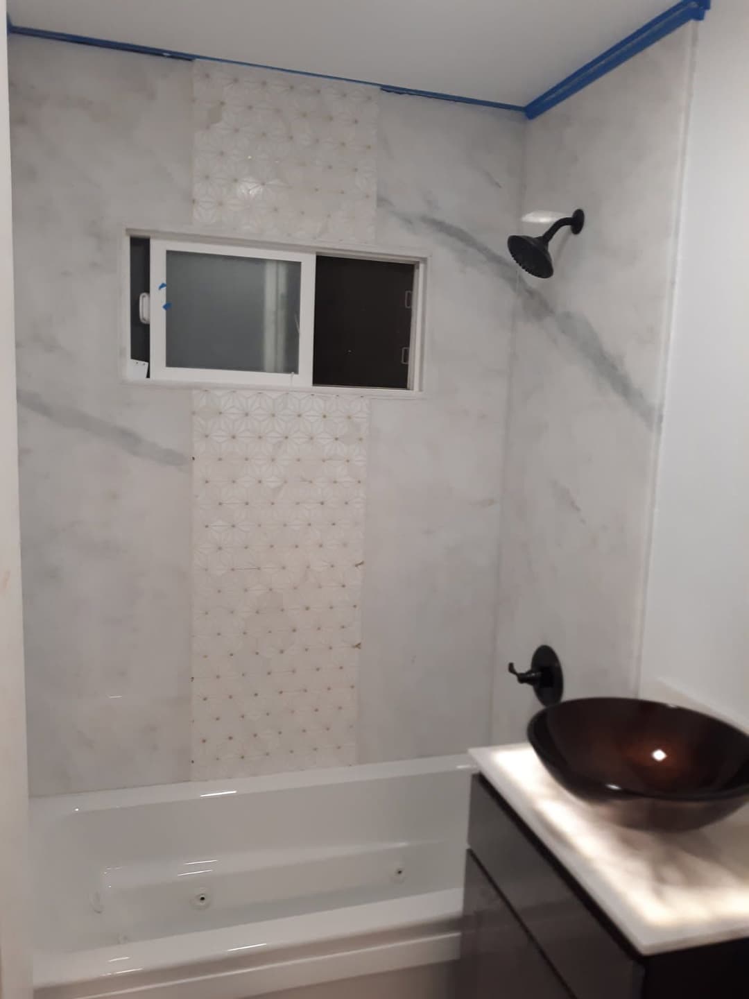Modern bathroom with marble walls, shower fixture, and stylish sink. Clean, elegant design.