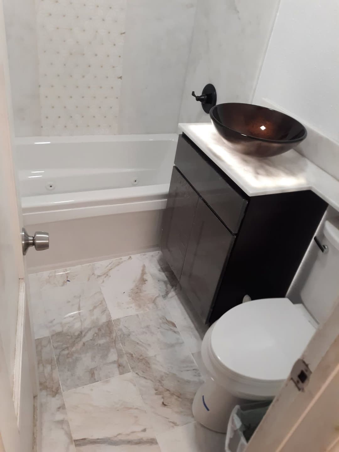 Modern bathroom with marble flooring, elegant black vanity, and stylish bowl sink.