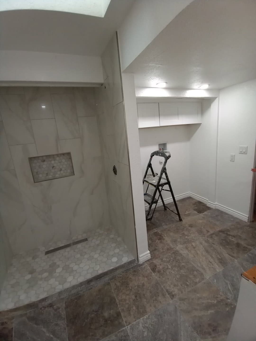 Modern bathroom remodel featuring a glass shower, marble tiles, and a stylish gray floor.
