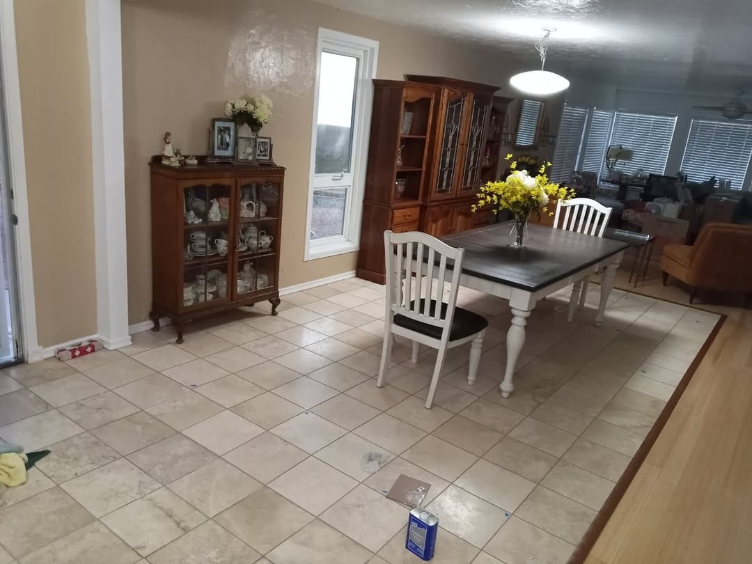 Bright dining area featuring a white table, chairs, wooden cabinet, and tiled floor.