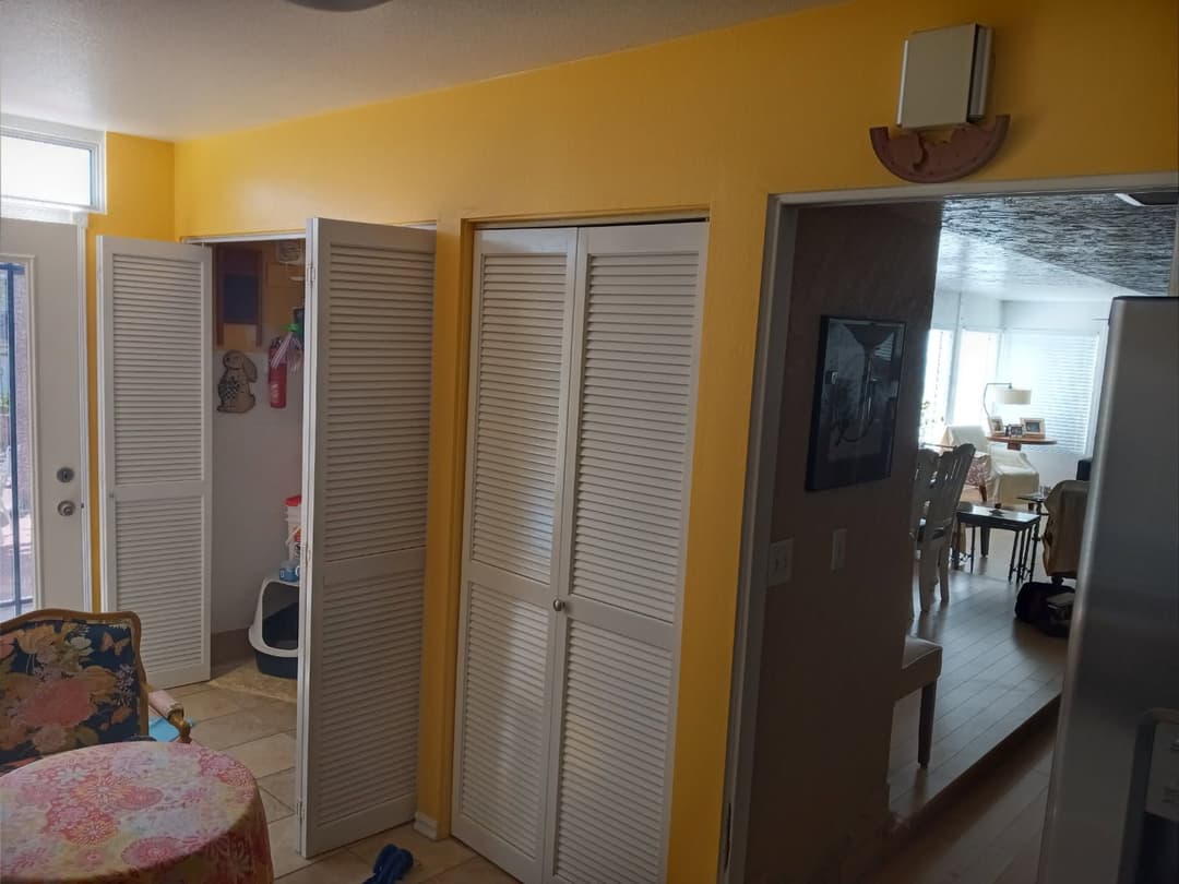 Bright yellow walls in a sunny room with closet doors and a view into a dining area.