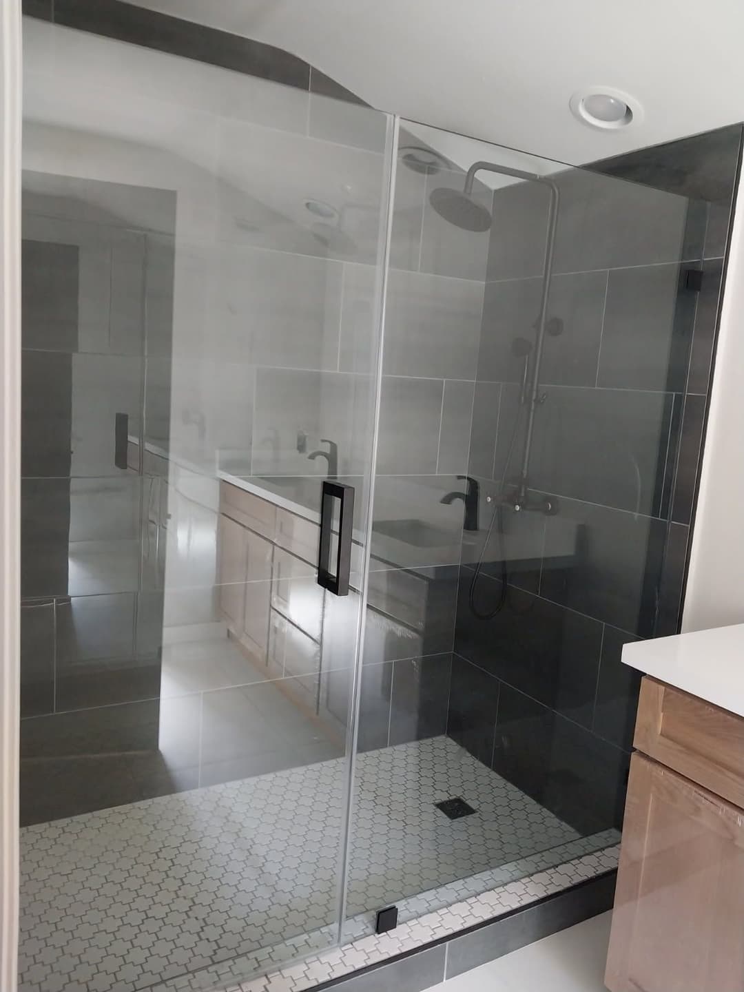 Modern glass shower enclosure with black tiles and stylish fixtures in a contemporary bathroom.
