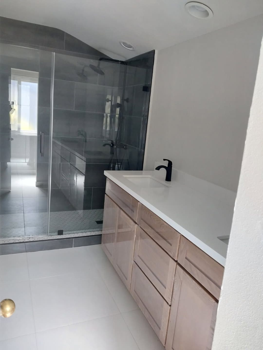 Modern bathroom featuring a glass shower, sleek countertop, and wooden cabinetry.