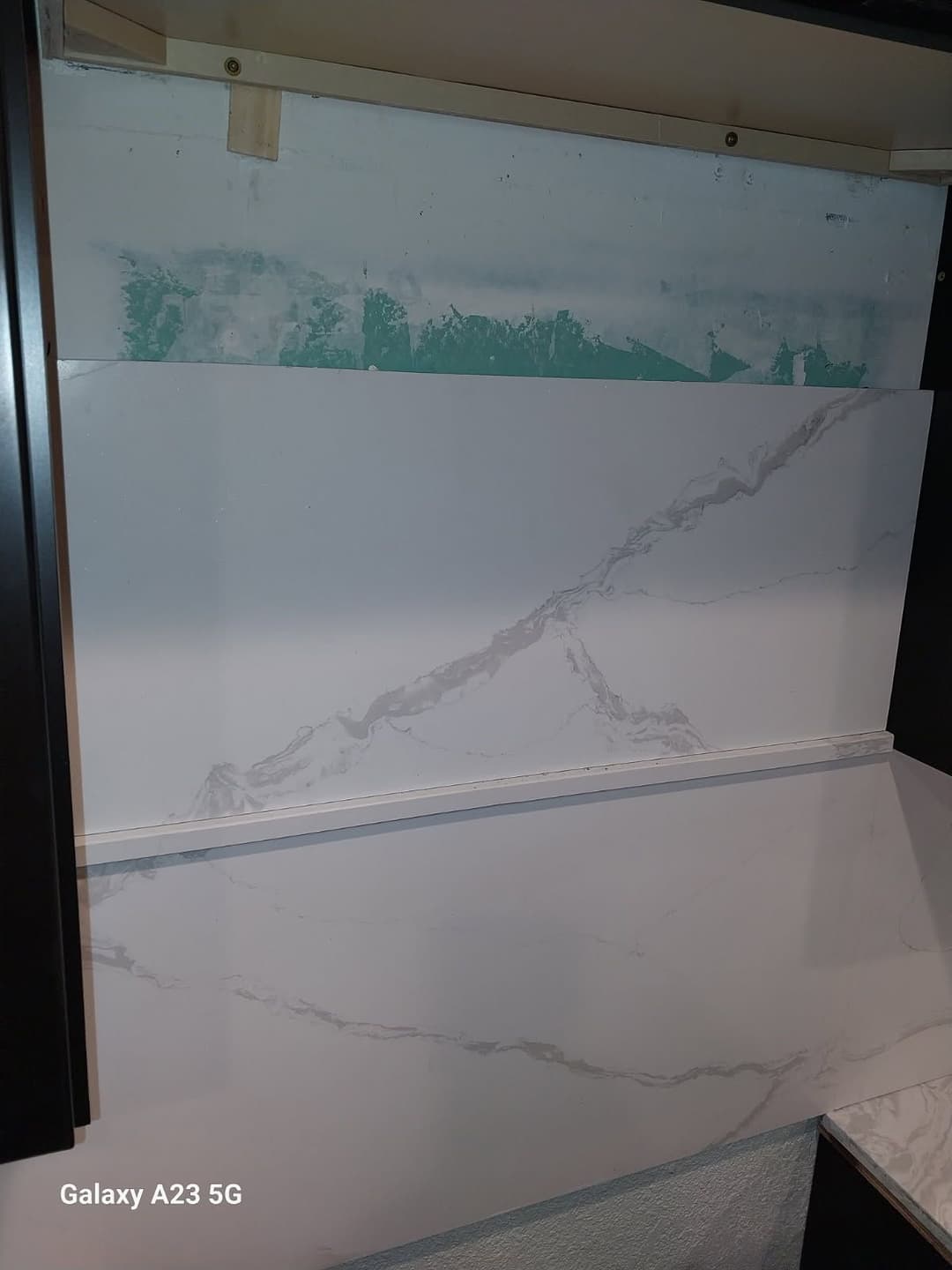Marble-patterned backsplash installation in a kitchen renovation project.
